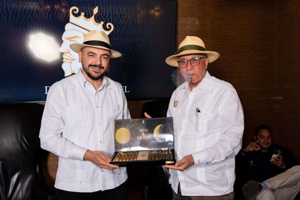 two men holding a box of sun and moon cigars on display